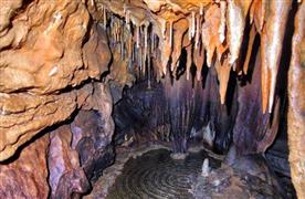 داخل غار «سراب امیدآباد» که استالاکتیت‌هایی در سقف و حوضچه‌ای در کف آن دیده می‌شود. 